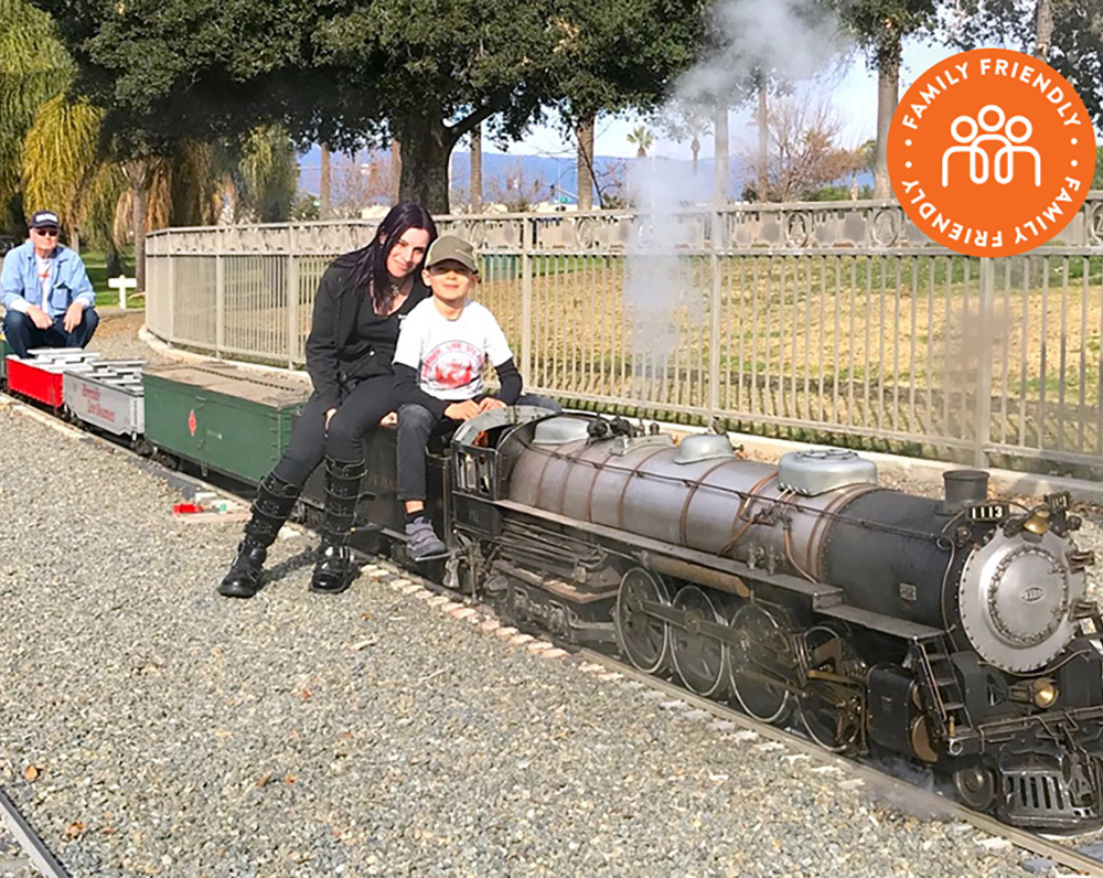 People posed next to a steam powered train. Image stamped with Family Friendly Badge